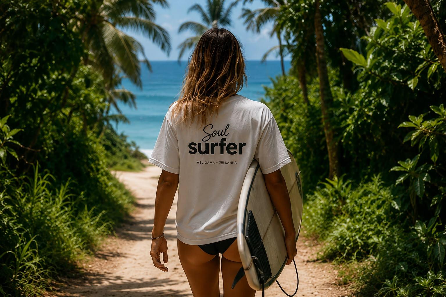 A surfer carrying a board along a jungle path down to the beach